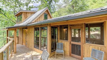 A wooden cabin with a deck, large windows, and a covered porch area.