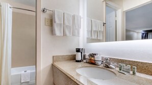 Ein Badezimmer mit Waschbecken, einer Kaffeemaschine und Pflegeprodukten.