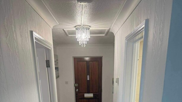 A hallway with wooden flooring, white walls, and a chandelier. - Apartment Sleeps 6 With Parking (Stanmore)