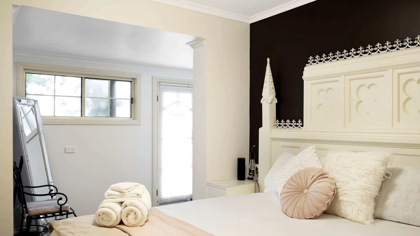 A bedroom with a bed, a window, and a chair.