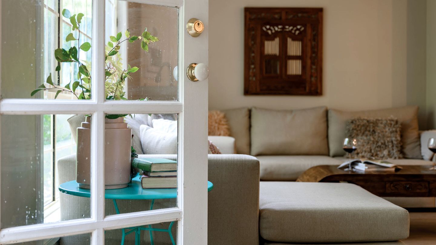 A living room with a sofa, a coffee table, and a window with a view of greenery outside.