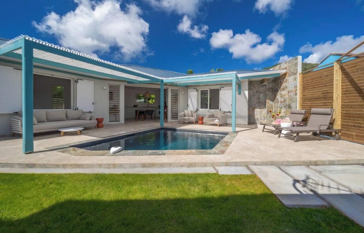 Un patio trasero con piscina, un porche cubierto y un conjunto de asientos.