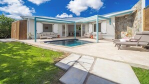 A modern outdoor living space with a pool, covered seating area, and a stone wall. - Creole Villas (10 people)•Swimming Pools•Beach within walking distance (Sainte-Luce)