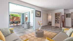 A modern living room with a sofa, a coffee table, and a dining area with chairs and a table. - Creole Villas (10 people)•Swimming Pools•Beach within walking distance (Sainte-Luce)