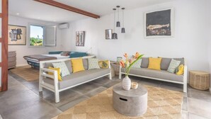 A modern living room with a sofa, a coffee table, and artwork on the walls. - Creole Villas (10 people)•Swimming Pools•Beach within walking distance (Sainte-Luce)