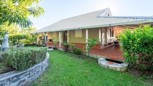 Ein Haus mit überdachter Veranda, einer Steinschmalseite und einem Rasen.