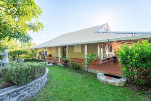 Ein Haus mit überdachter Veranda, einer Steinschmalseite und einem Rasen.