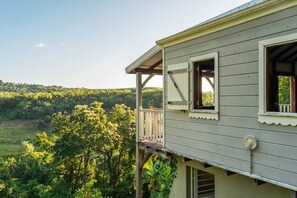 A two-story building with a balcony overlooking a forested landscape. - Coffee Plantation House, Villa & Bungalow with Ocean View (Le Carbet)
