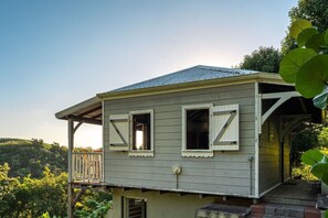 A two-story house with a porch, a small deck, and a metal roof. - Coffee Plantation House, Villa & Bungalow with Ocean View (Le Carbet)