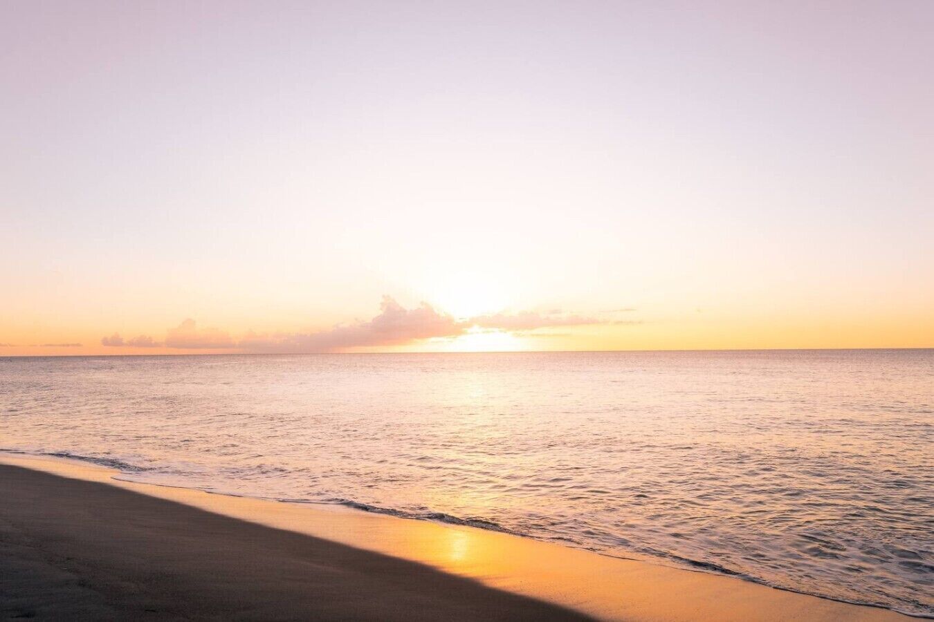 A beach with a calm sea and a clear sky.