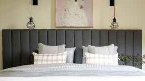 A bed with a grey upholstered headboard, two black pendant lights, and a framed artwork above. - Stunning, Secluded, Rustic Cabin in Daylesford, Victoria (Daylesford)