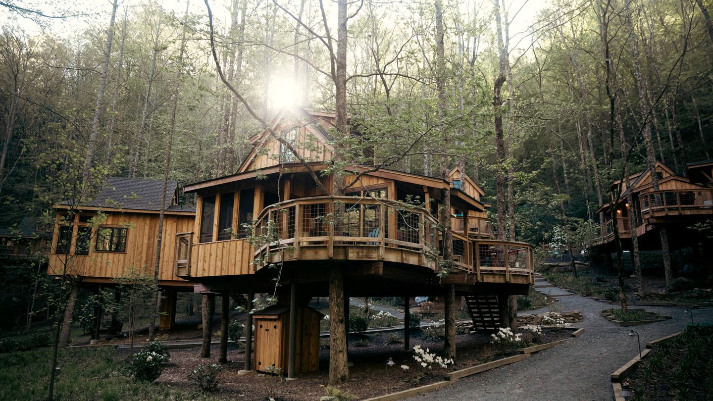 A wooden cabin with a balcony, surrounded by trees.
