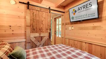 A wooden interior with a bed, a sliding barn door, and a sign for AYRES Vacation Rentals.