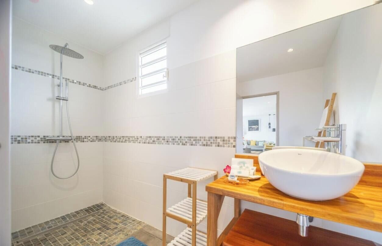 Une salle de bain moderne avec un grand lavabo, une douche et un petit tabouret.