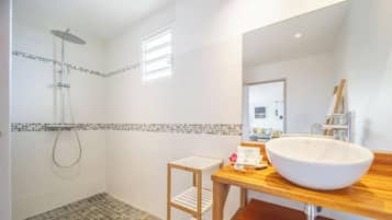 Une salle de bain moderne avec un grand lavabo, une douche et un petit tabouret.