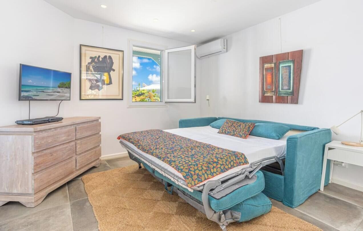 Een slaapkamer met een bed, een dressoir, een televisie en kunstwerken aan de muur.