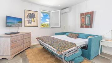 Een slaapkamer met een bed, een dressoir, een televisie en kunstwerken aan de muur.