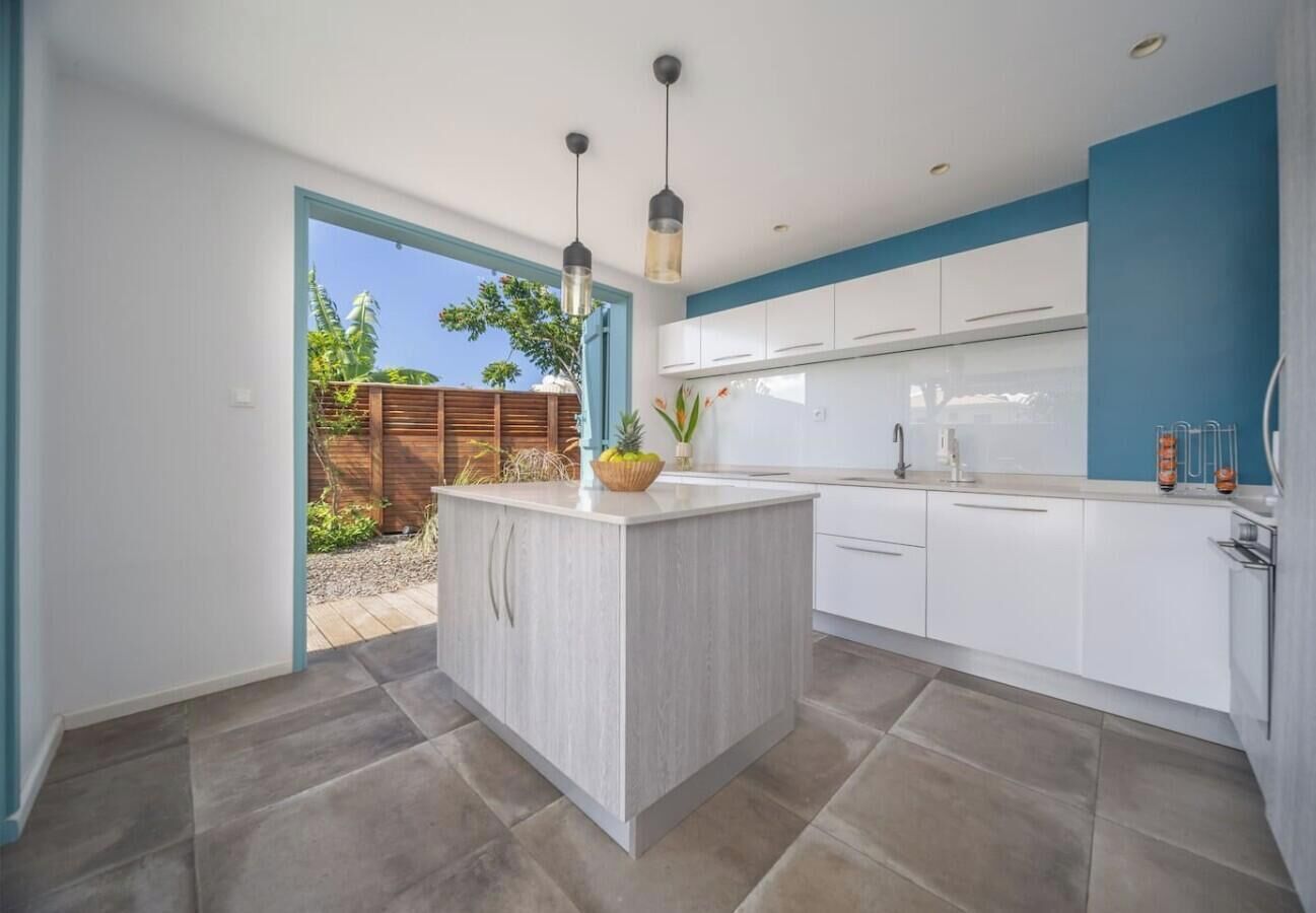 A modern kitchen with a central island, white cabinets, and a blue accent wall.