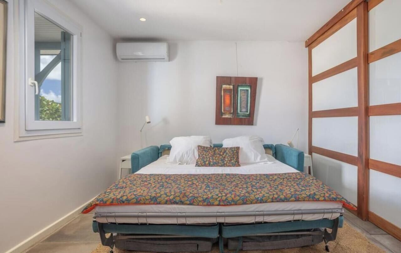 Ein Schlafzimmer mit Bett, Fenster, Klimaanlage und einer Schiebetür.