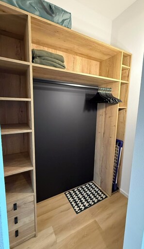 Una habitación con un armario, una puerta negra, un tapete estampado y una pared azul.