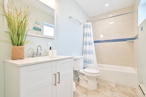 A bathroom with a sink, toilet, and shower area. - Seaside Retreat: Salty Shore Getaway (Wildwood)