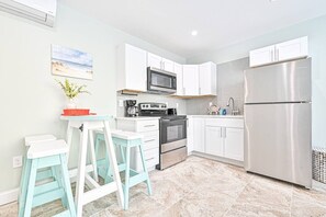 A modern kitchen with white cabinetry, stainless steel appliances, and a tiled floor. - Seaside Retreat: Salty Shore Getaway (Wildwood)
