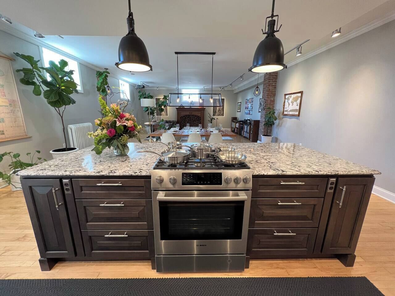 Una cocina con una isla central, iluminación doble en el techo y un horno empotrado.