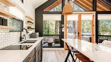 A modern kitchen with a large island, a dining area with a view, and a balcony with outdoor seating.