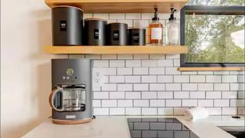 Una cucina con piastrelle bianche a metrò, mensole in legno e una macchina da caffè.