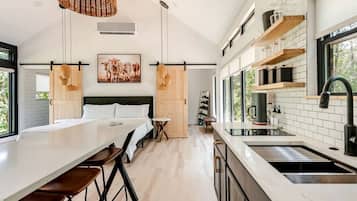 A modern kitchen with a central island, a dining area with a long table and chairs, and a large window providing natural light.