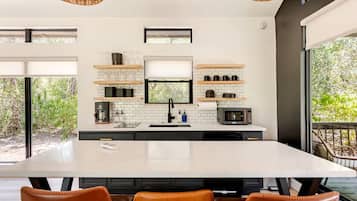 A modern kitchen with a large island, built-in appliances, and a view of greenery outside.