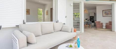 Un salon moderne avec un canapé, une table basse et un coin repas visible au fond.