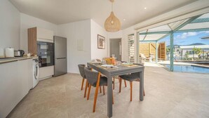 A modern kitchen with a dining area and a view of a swimming pool. - An Ti Doucè—Villa with a pool, 300 meters from the beach (Sainte-Luce)