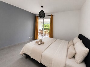 Quarto com cama, luminária pendente e vista para um pátio externo.