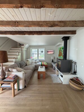 Un salon chaleureux avec un canapé, une table basse, une cheminée et un escalier.