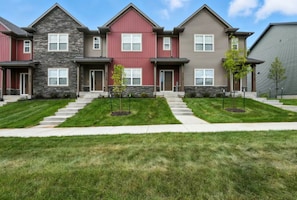 A row of townhouses with a central walkway, front doors, and small front yards.
