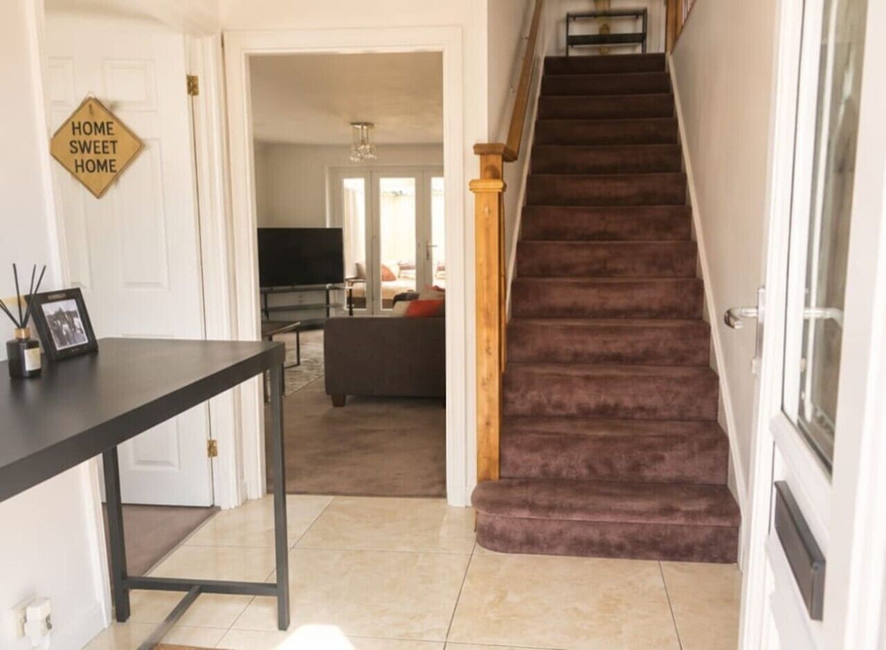 Un escalier menant à un espace de vie comprenant un canapé et un téléviseur.