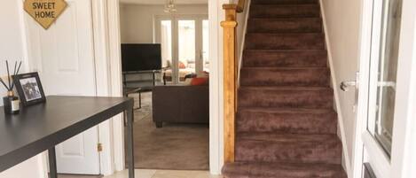 A staircase leading to a living area with a sofa and a TV.
