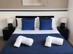 A hotel room with a large bed, two nightstands, and a wall-mounted artwork.
