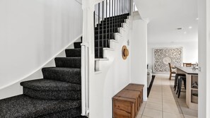 Eine Treppe mit schwarzem Teppich, die zu einem hellen Innenraum führt.