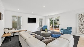 Ein modernes Wohnzimmer mit einer Couch, einem Couchtisch und einem an der Wand befestigten Fernseher.