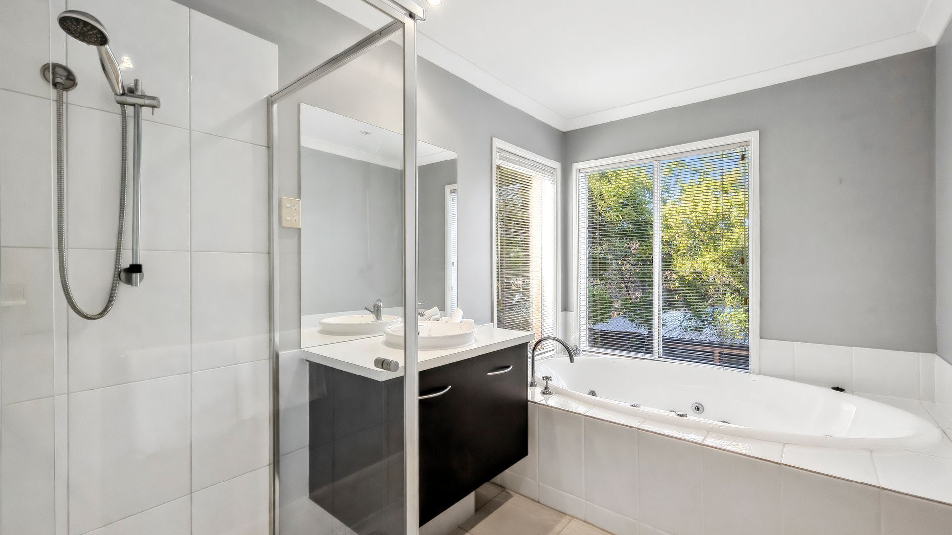 Un baño moderno con cabina de ducha de vidrio, una bañera independiente y un tocador con espejo.