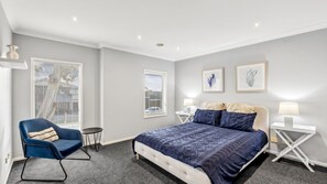 Ein Schlafzimmer mit einem Bett, einem Sessel, zwei Nachttischen und zwei Wandlampen.