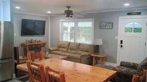Un espacio habitable compacto con una mesa de comedor, sillas, un sofá, un televisor y un ventilador de techo.