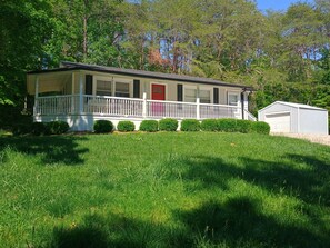 A single-story house with a front porch, a red door, and a small attached garage.