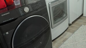 A Samsung washing machine and dryer in a laundry room with a patterned rug and a white refrigerator in the background. - Peaceful 3-bedroom house in delightful Clarkson (Clarkson)