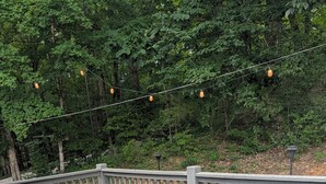 An outdoor deck with a wicker sofa, two matching ottomans, and a patterned rug. - Peaceful 3-bedroom house in delightful Clarkson (Clarkson)