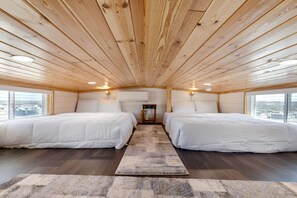 A cabin with two beds, a central door, and a view through large windows. - Charming and Modern Tiny Home Escape with Resort Amenities and Pool Near Fredericksburg, TX (Fredericksburg)