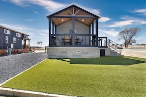 Un bâtiment moderne doté d’un espace extérieur aménagé et abrité, d’une base en pierre et d’une pelouse verdoyante.