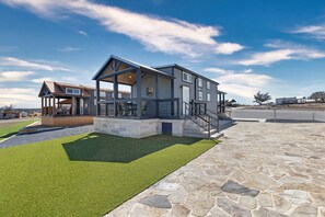 A modern two-story house with a covered patio, stone pathway, and a well-maintained lawn. - Charming and Modern Tiny Home Escape with Resort Amenities and Pool Near Fredericksburg, TX (Fredericksburg)
